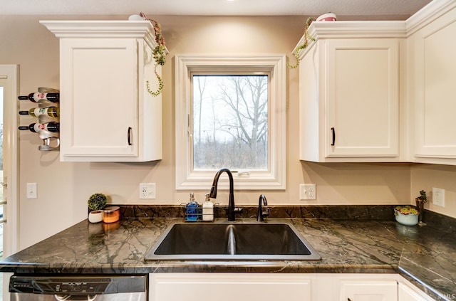 kitchen featuring stainless steel dishwasher, a sink, and white cabinetry