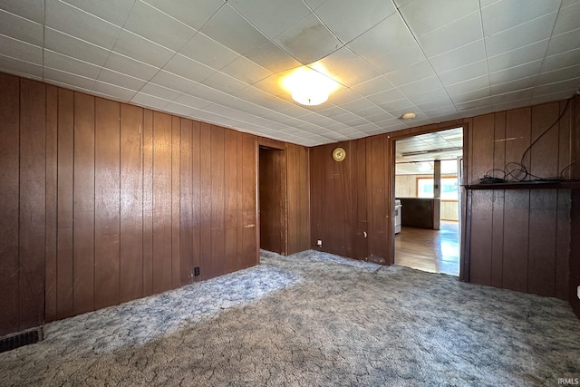 unfurnished room with wooden walls and carpet flooring