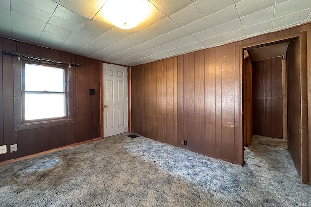 empty room with carpet flooring and wood walls