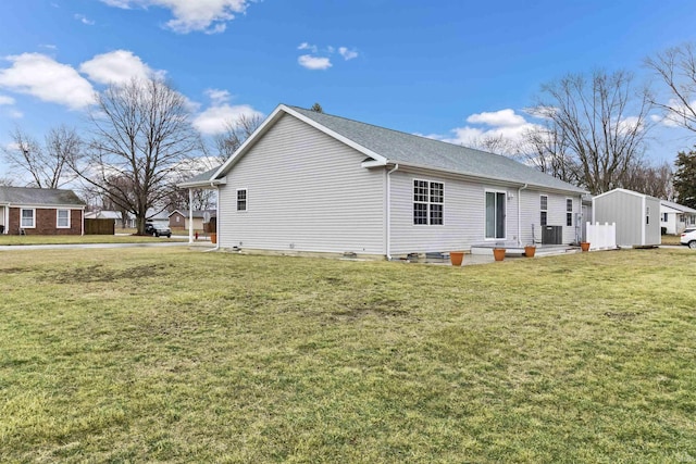 rear view of house with central AC and a lawn