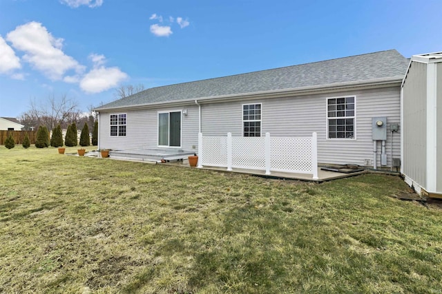 back of property with a yard and a shingled roof