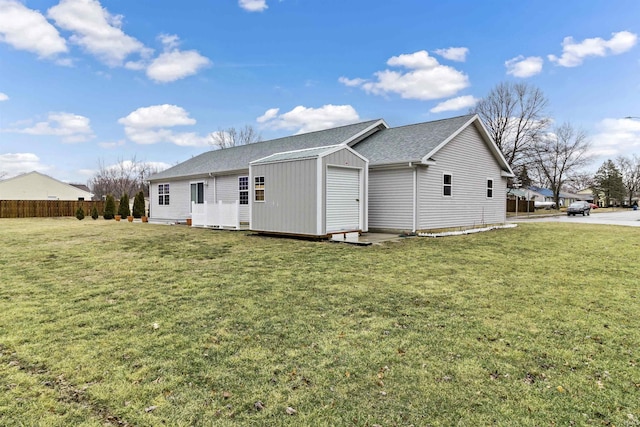 rear view of house with a lawn and fence