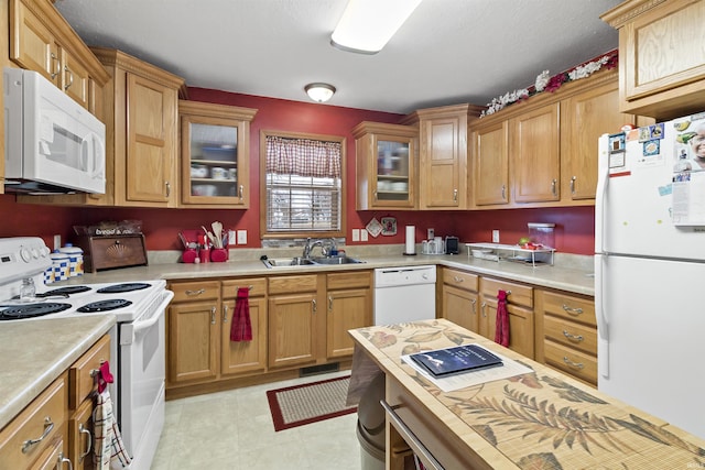 kitchen featuring light countertops, visible vents, glass insert cabinets, a sink, and white appliances