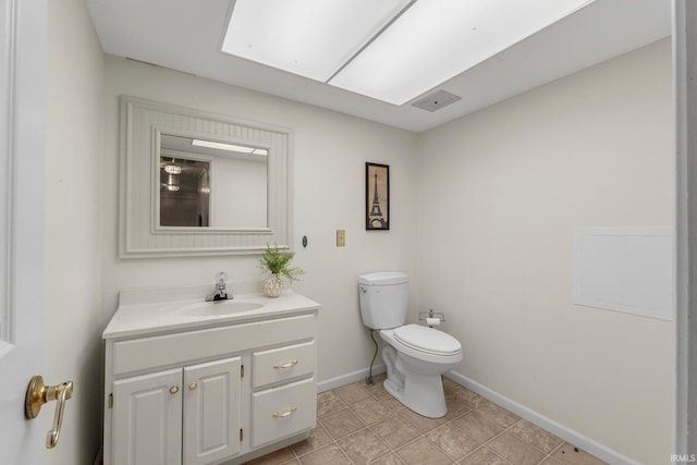 bathroom featuring a skylight, visible vents, toilet, vanity, and baseboards