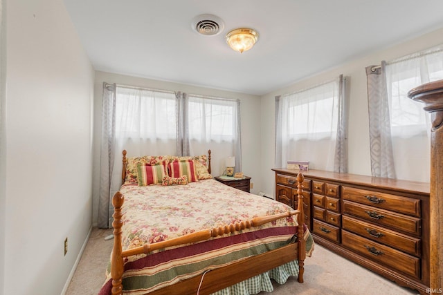 bedroom featuring baseboards, visible vents, and light colored carpet