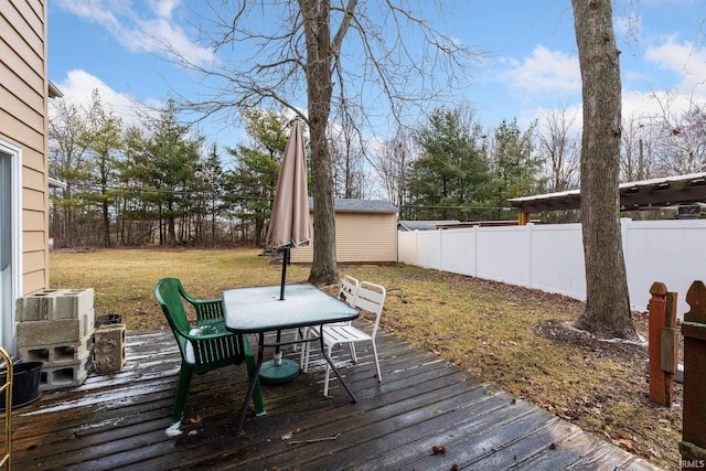 wooden deck with outdoor dining space, a fenced backyard, an outbuilding, and a storage unit