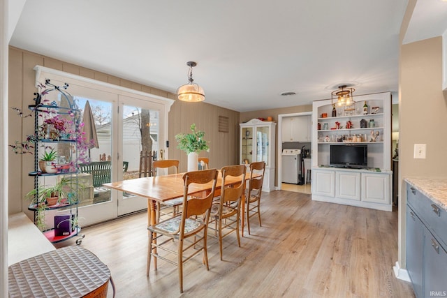 dining space with washer / dryer and light wood-style floors