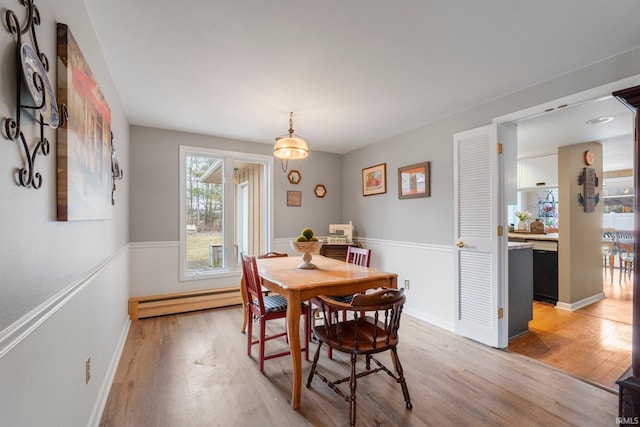 dining space with light wood finished floors, baseboard heating, and baseboards