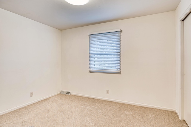 spare room with carpet, visible vents, and baseboards