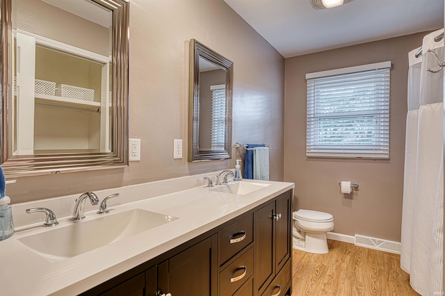 bathroom featuring toilet, visible vents, a sink, and wood finished floors