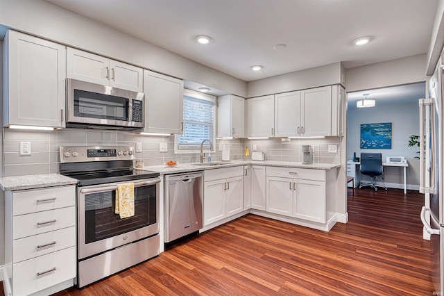 kitchen featuring stainless steel appliances, dark wood-style flooring, a sink, and white cabinets