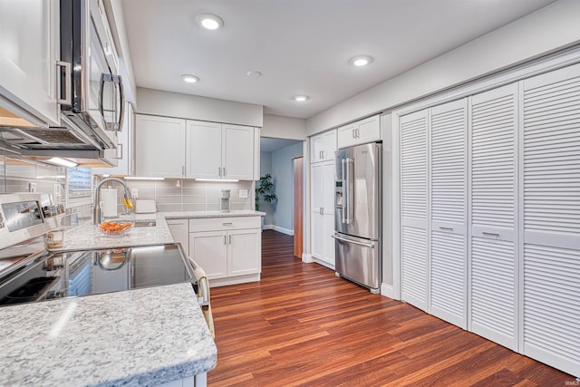 kitchen with decorative backsplash, dark wood-style floors, appliances with stainless steel finishes, white cabinetry, and recessed lighting