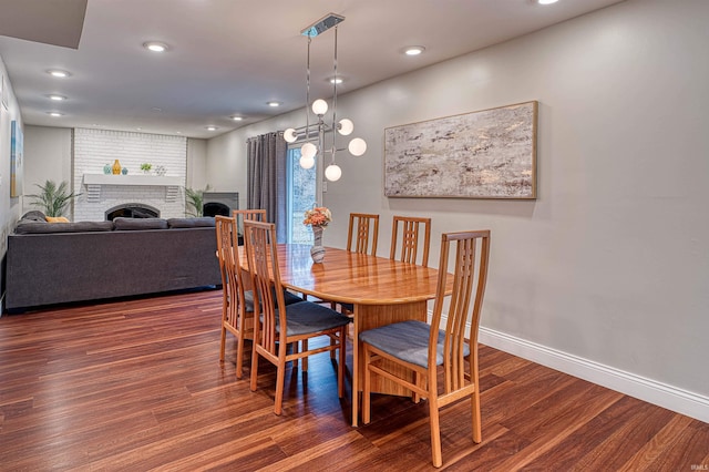 dining room with a brick fireplace, baseboards, wood finished floors, and recessed lighting