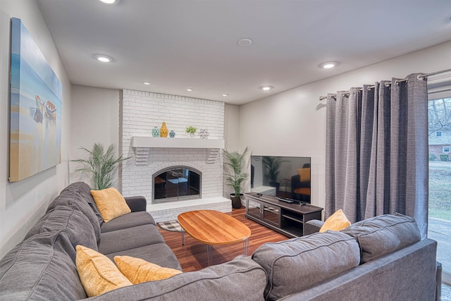 living area featuring recessed lighting, a brick fireplace, and wood finished floors