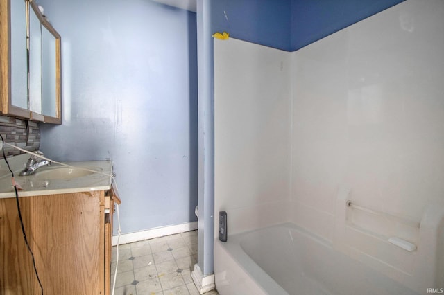 bathroom with vanity, baseboards, shower / bathing tub combination, backsplash, and tile patterned floors