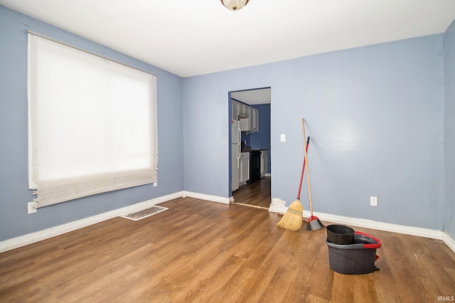 empty room featuring visible vents, baseboards, and wood finished floors