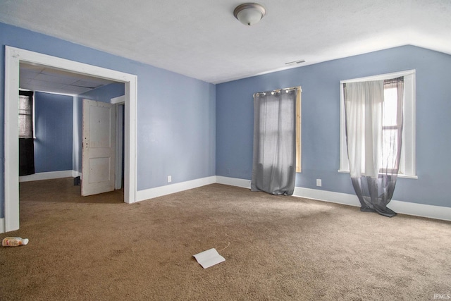 unfurnished room with carpet, visible vents, and baseboards