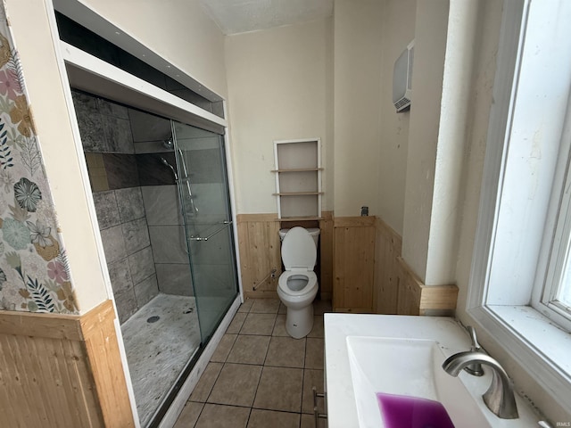 bathroom featuring a wainscoted wall, tile patterned flooring, toilet, and a shower stall