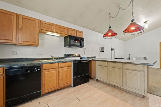 kitchen featuring lofted ceiling, a peninsula, a sink, black appliances, and light wood finished floors