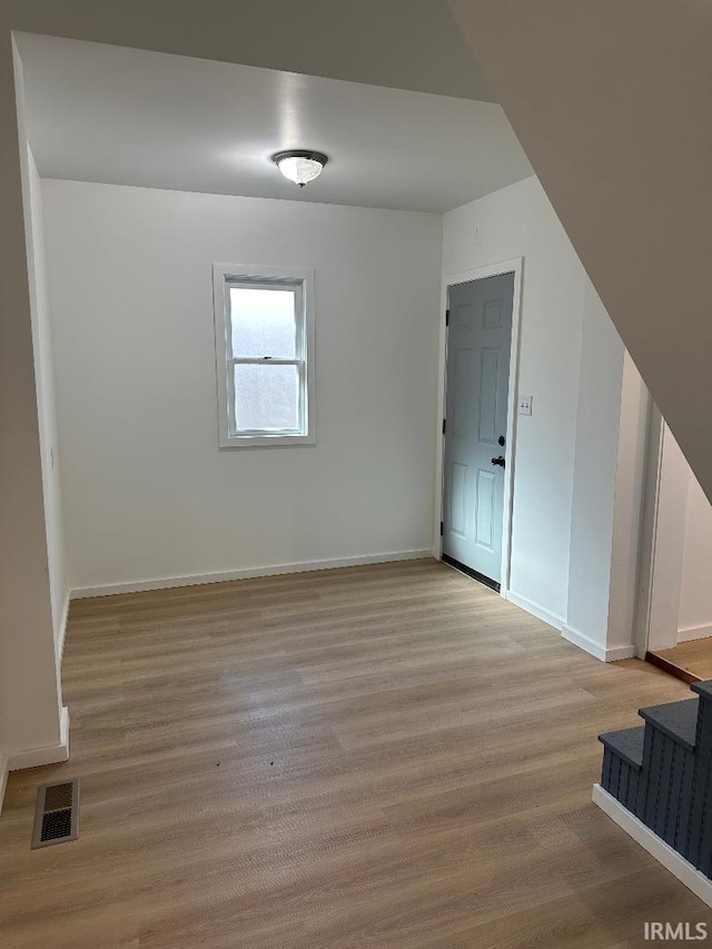 empty room with light wood-style floors, visible vents, and baseboards