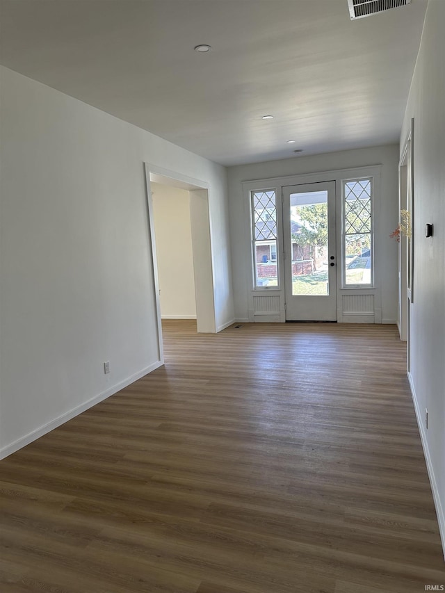 spare room featuring visible vents, baseboards, and wood finished floors