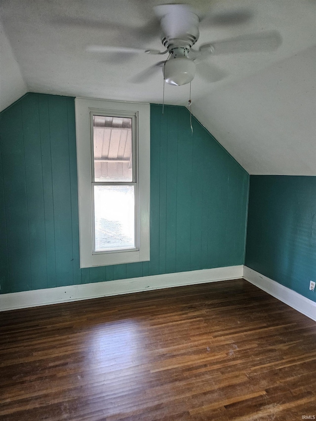 bonus room featuring dark wood-type flooring, vaulted ceiling, baseboards, and a ceiling fan