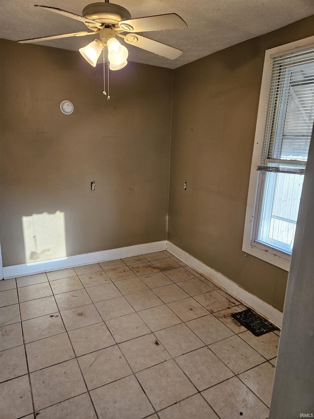 unfurnished room with light tile patterned flooring, ceiling fan, a textured ceiling, and baseboards