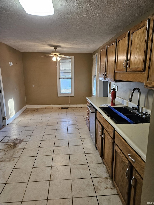 kitchen with light tile patterned floors, a sink, a ceiling fan, light countertops, and dishwasher