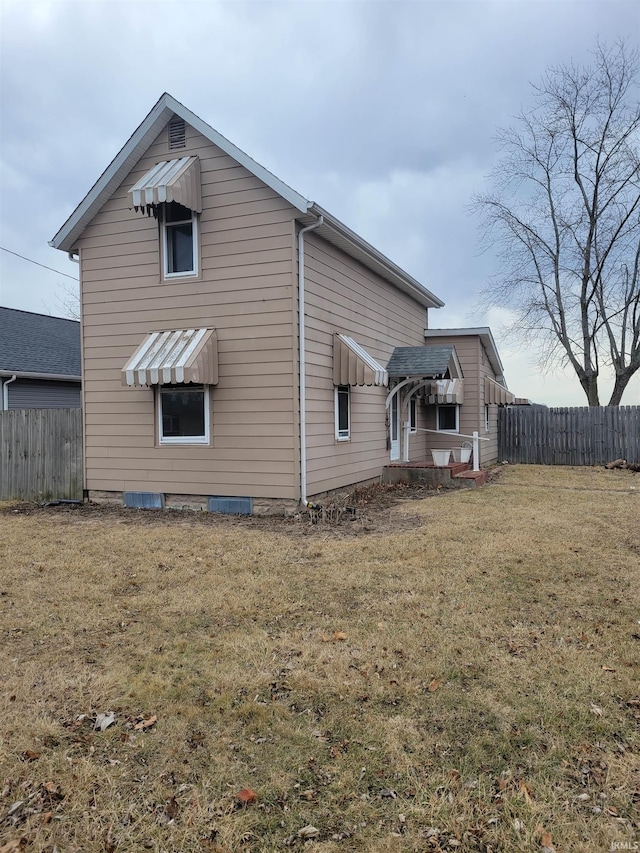 back of property with a lawn and fence