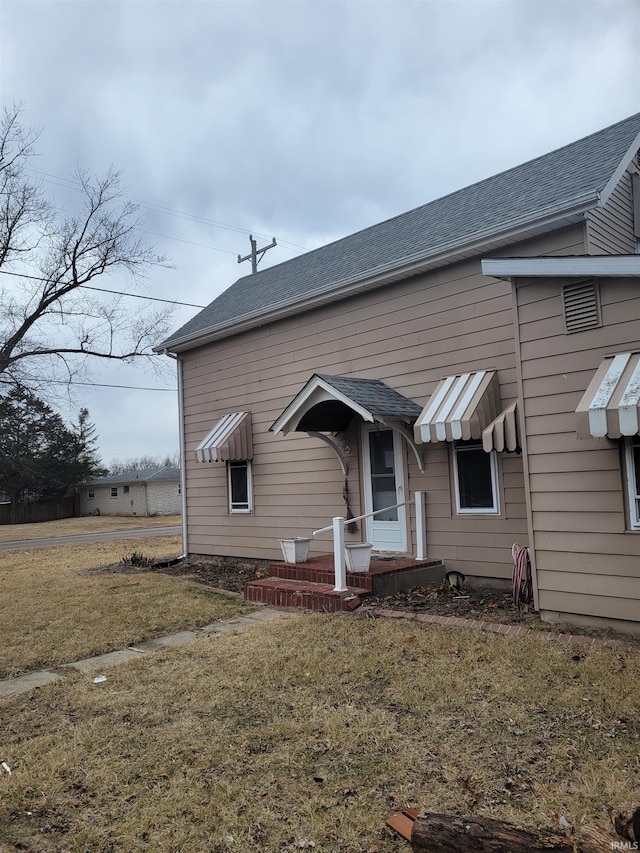 view of front facade with roof with shingles and a front yard