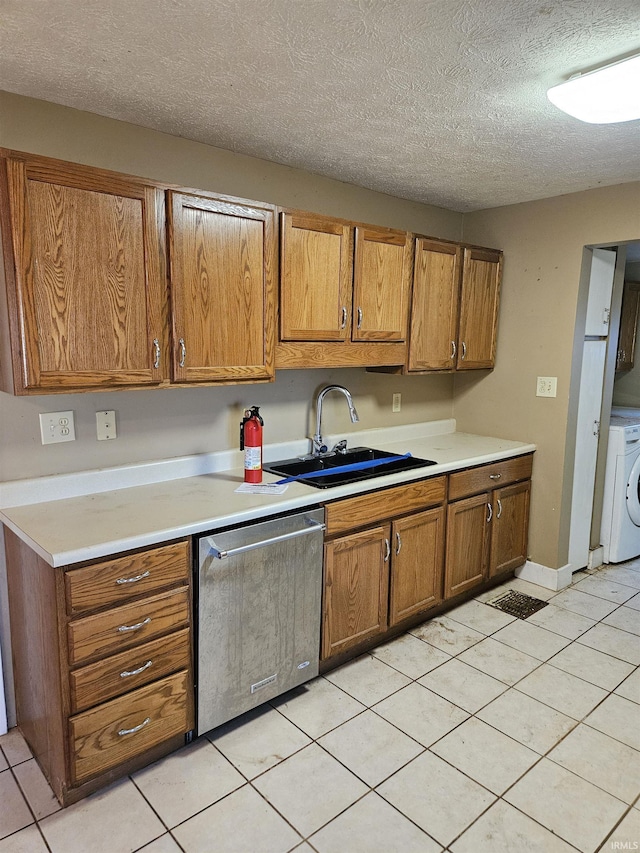 kitchen with brown cabinetry, washer / clothes dryer, light countertops, stainless steel dishwasher, and a sink