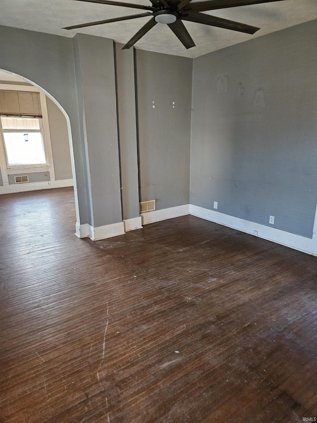 spare room with arched walkways, baseboards, visible vents, and hardwood / wood-style floors