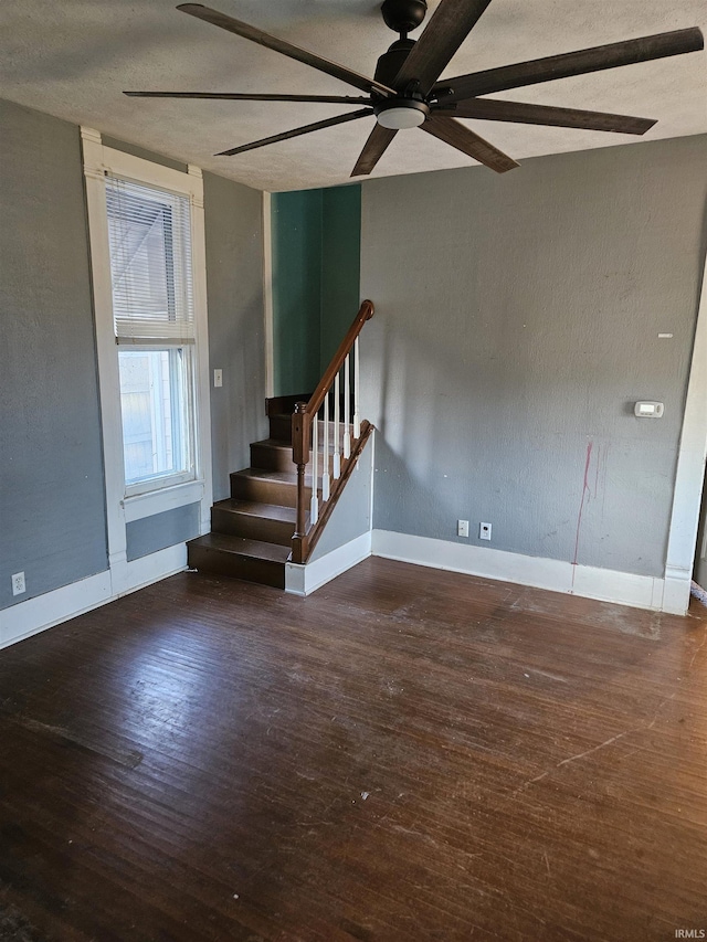 empty room featuring stairway, ceiling fan, a textured ceiling, wood finished floors, and baseboards