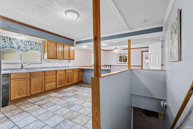 kitchen featuring dishwasher, brown cabinets, light countertops, a textured ceiling, and a sink