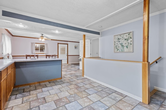 kitchen with a textured ceiling, baseboards, light countertops, and a ceiling fan