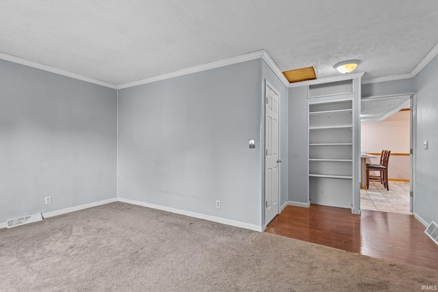 carpeted spare room with baseboards, visible vents, a textured ceiling, and ornamental molding