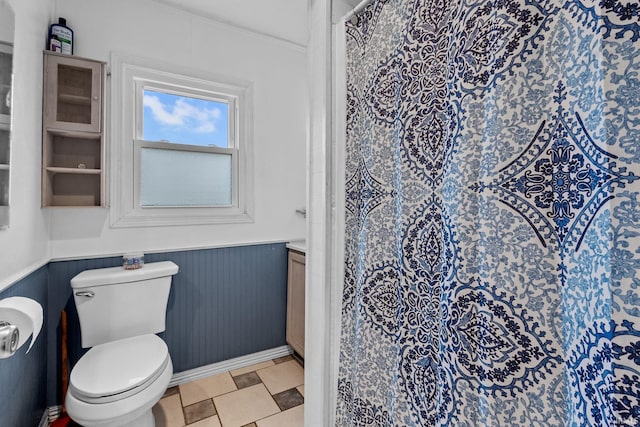 bathroom with curtained shower, wainscoting, and toilet