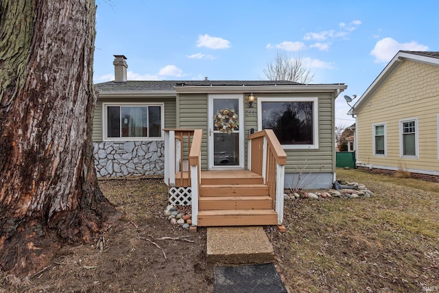 exterior space featuring stone siding and a chimney