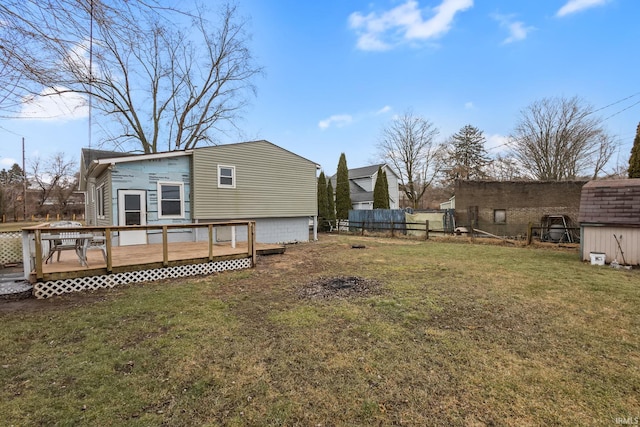 rear view of house featuring a yard, fence, and a wooden deck