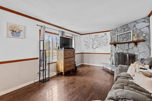 living room featuring a textured ceiling, ornamental molding, a fireplace, and wood finished floors