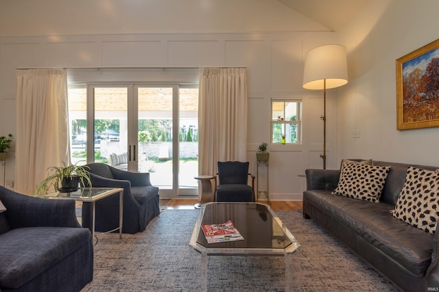 living area with vaulted ceiling, wood finished floors, and a decorative wall