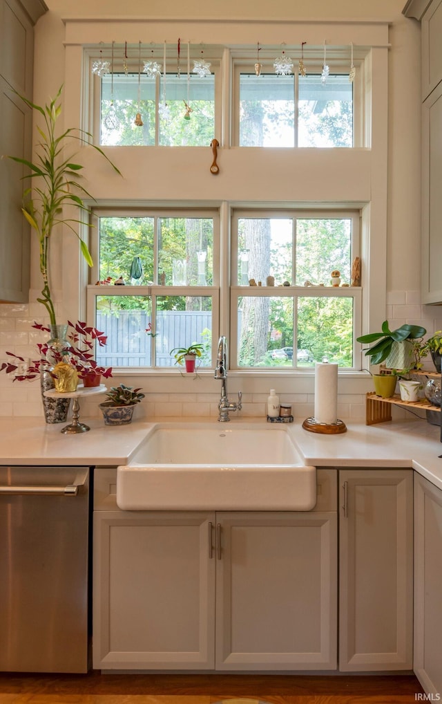 kitchen featuring tasteful backsplash, light countertops, a sink, and stainless steel dishwasher