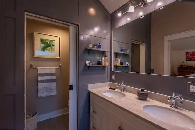 full bathroom with double vanity, baseboards, a sink, and tile patterned floors