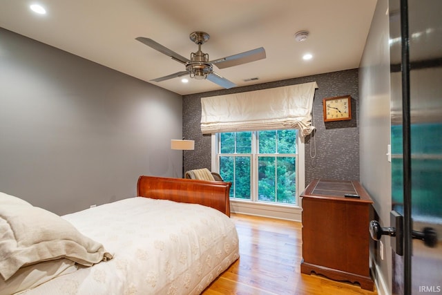 bedroom featuring light wood-style flooring, recessed lighting, an accent wall, visible vents, and wallpapered walls