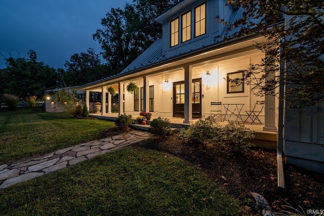 view of front facade featuring metal roof, stucco siding, a porch, and a front yard