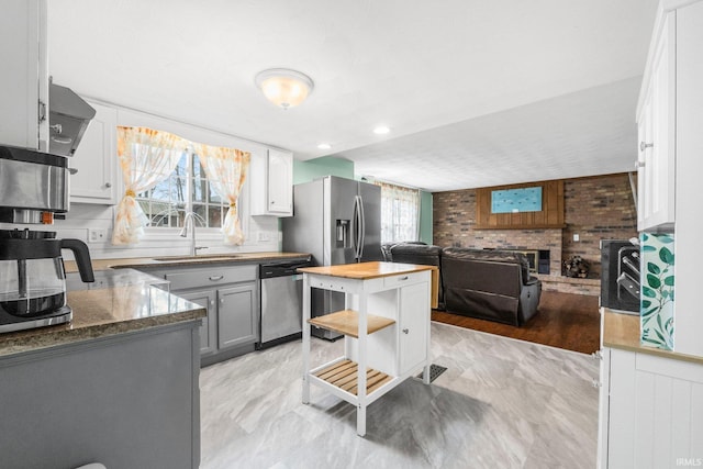 kitchen with plenty of natural light, a fireplace, appliances with stainless steel finishes, and a sink