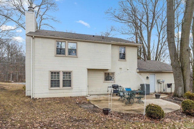 rear view of house featuring cooling unit, a patio, and a chimney