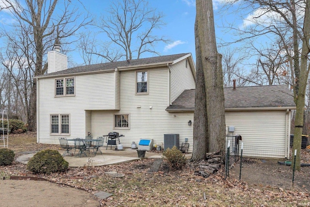 back of property featuring roof with shingles, a patio, and a chimney