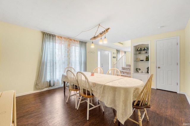 dining room with built in features, baseboards, stairway, and dark wood-type flooring