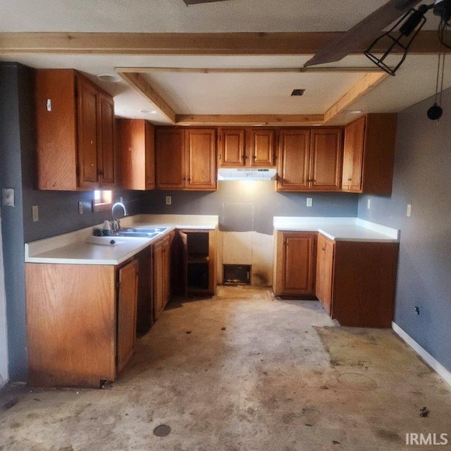 kitchen with under cabinet range hood, baseboards, brown cabinetry, and a sink